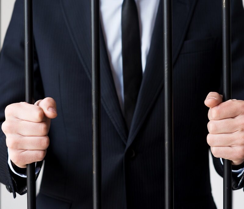 Businessmen in prison. Cropped image of man in formalwear standing behind a prison cell